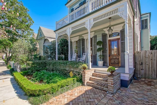 view of exterior entry featuring a porch and fence