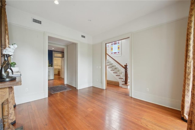 unfurnished living room with stairs, hardwood / wood-style floors, baseboards, and recessed lighting
