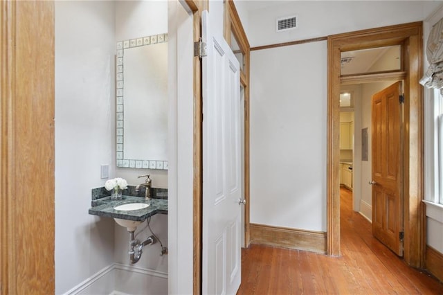 hall with wood finished floors, a sink, and baseboards