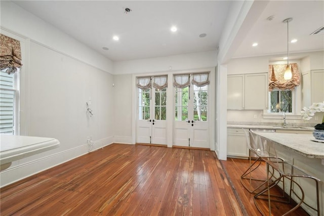 unfurnished dining area featuring hardwood / wood-style floors, a sink, baseboards, and recessed lighting