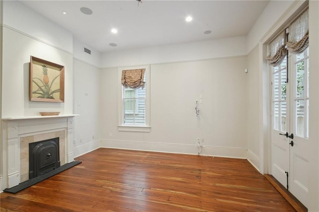 unfurnished living room featuring hardwood / wood-style flooring, baseboards, a tiled fireplace, and recessed lighting
