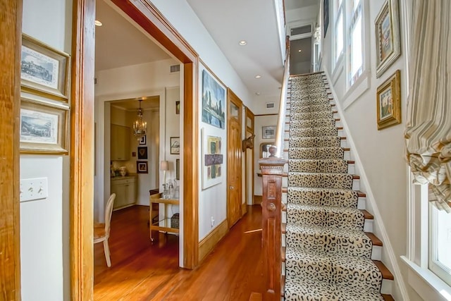 staircase with wood finished floors and recessed lighting