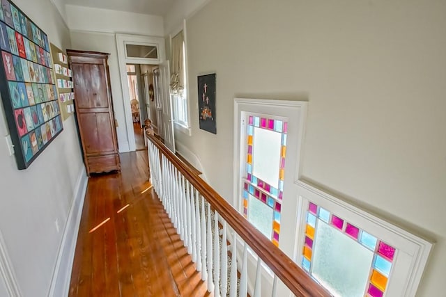 hall with an upstairs landing, wood finished floors, and baseboards