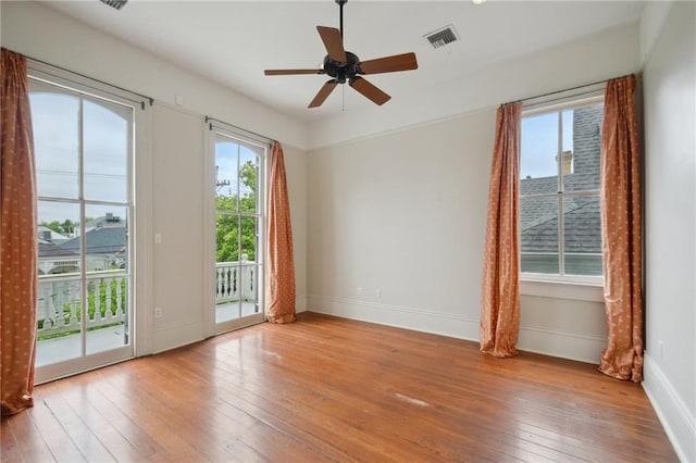 spare room featuring hardwood / wood-style floors, plenty of natural light, and baseboards