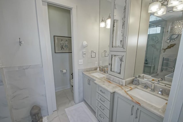 full bathroom with toilet, a shower stall, double vanity, a chandelier, and marble finish floors