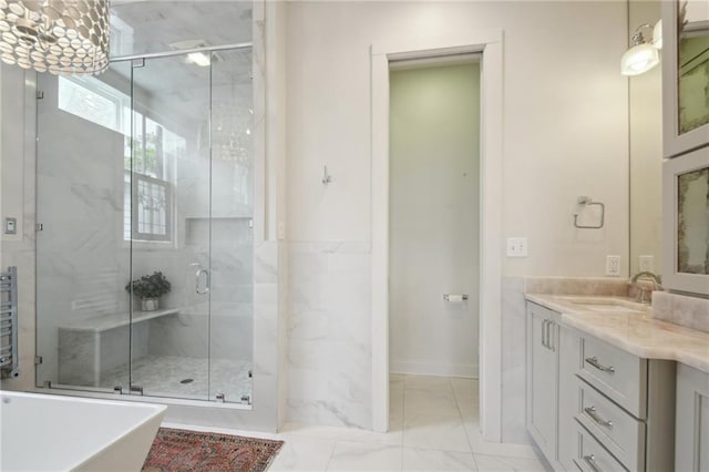 bathroom featuring a shower stall, vanity, marble look tile flooring, and a freestanding tub