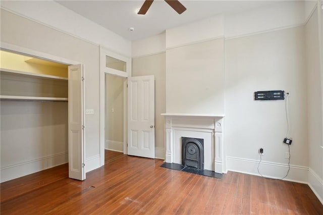 unfurnished living room featuring a ceiling fan, wood finished floors, a fireplace with flush hearth, and baseboards