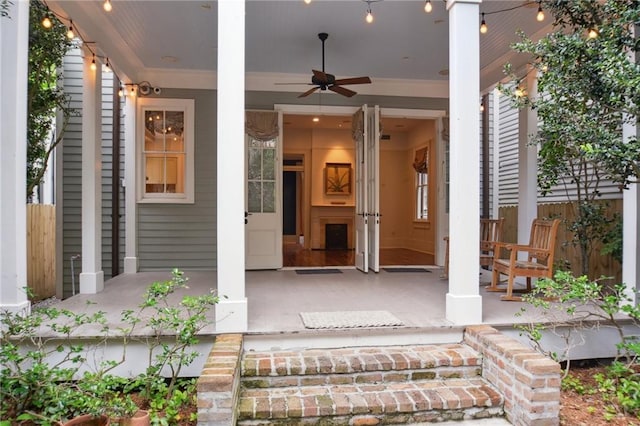 entrance to property with covered porch, a ceiling fan, and fence