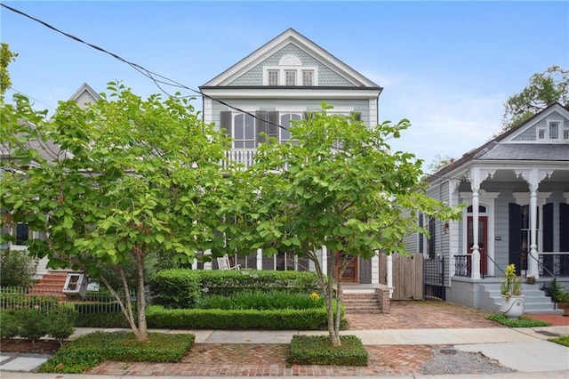 victorian house featuring covered porch and fence