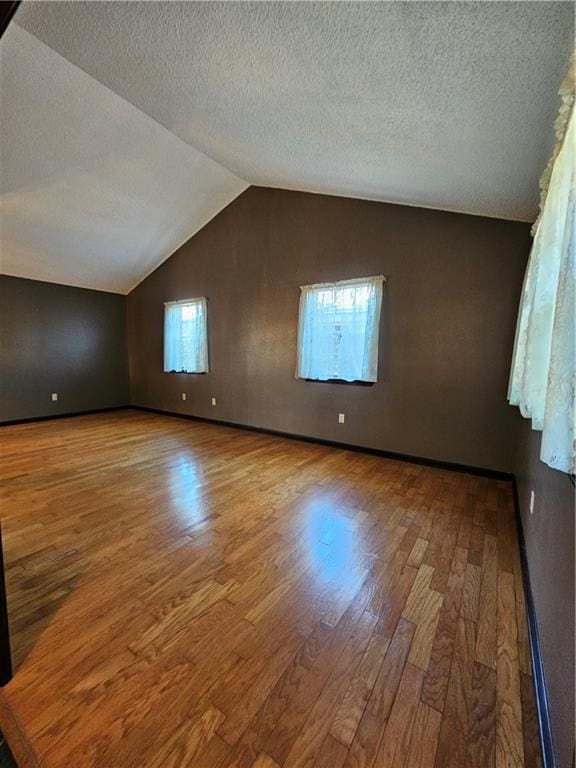 bonus room with a textured ceiling, wood finished floors, and vaulted ceiling