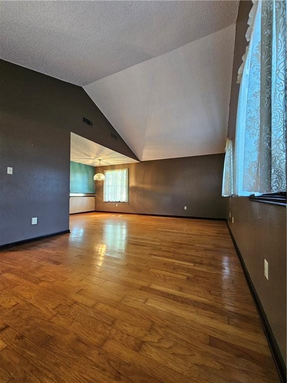 interior space with visible vents, baseboards, wood finished floors, and lofted ceiling