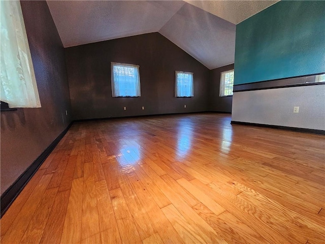 interior space featuring hardwood / wood-style floors, baseboards, and vaulted ceiling