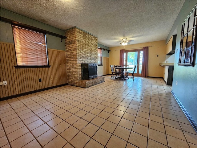 unfurnished living room featuring a textured ceiling, ceiling fan, baseboards, and a brick fireplace