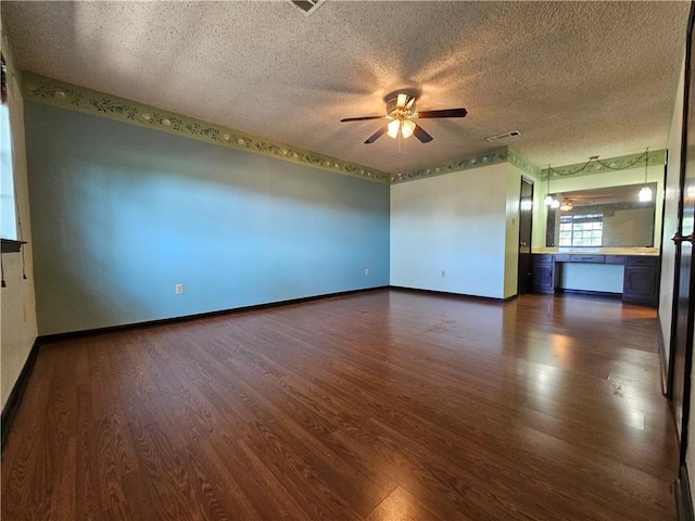 spare room with a textured ceiling, ceiling fan, and dark wood finished floors