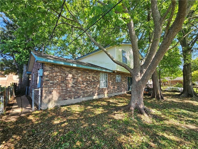 view of side of home featuring fence and brick siding