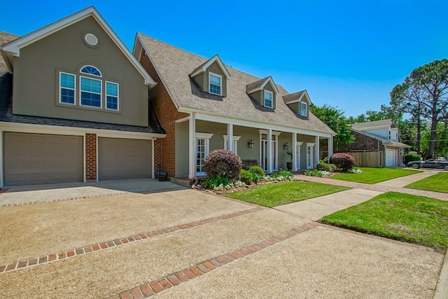 cape cod house featuring an attached garage, covered porch, concrete driveway, a front yard, and roof with shingles