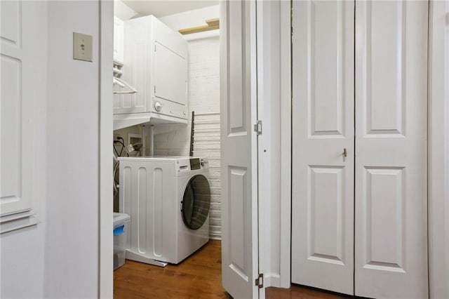 3915 St Charles Ave Unit 215, New Orleans, LA 70118 - washroom featuring estacked washer and dryer and dark wood-style flooring