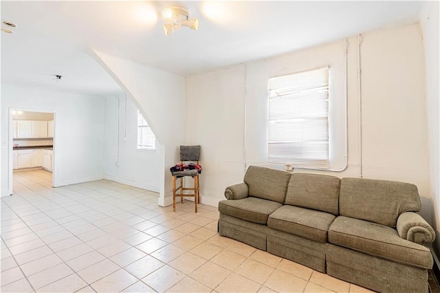 living area with arched walkways, baseboards, and light tile patterned floors
