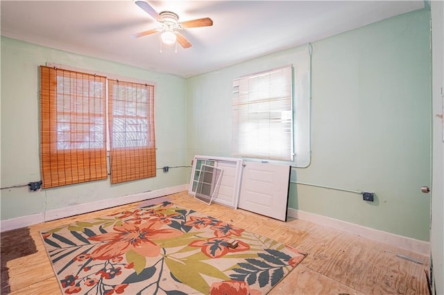 empty room with baseboards, ceiling fan, and light wood-type flooring