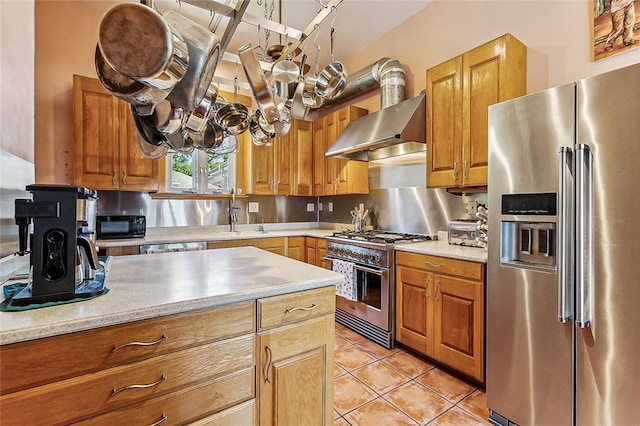 3418 Coliseum St, New Orleans, LA 70115 - kitchen featuring high quality appliances, a sink, brown cabinets, light tile patterned floors, and wall chimney exhaust hood