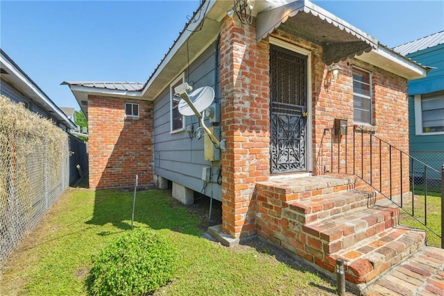 2617 Danneel St, New Orleans, LA 70113 - exterior space with brick siding, metal roof, fence, and a lawn