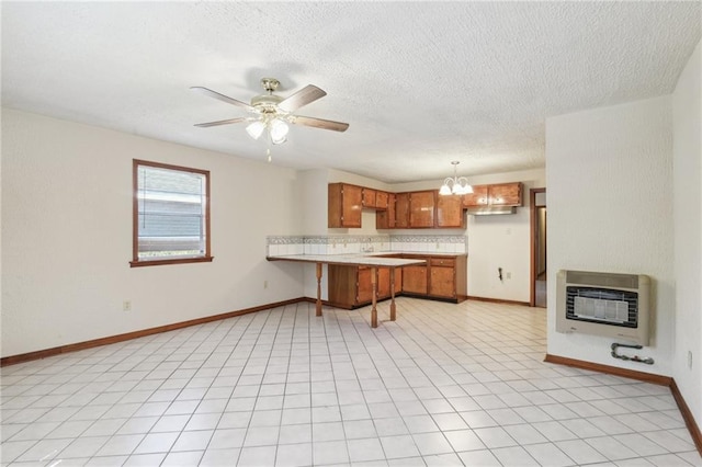 2617 Danneel St, New Orleans, LA 70113 - kitchen with baseboards, a peninsula, light countertops, heating unit, and brown cabinetry