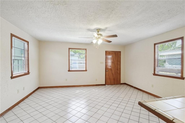 2617 Danneel St, New Orleans, LA 70113 - empty room featuring a textured ceiling, light tile patterned floors, a ceiling fan, and plenty of natural light