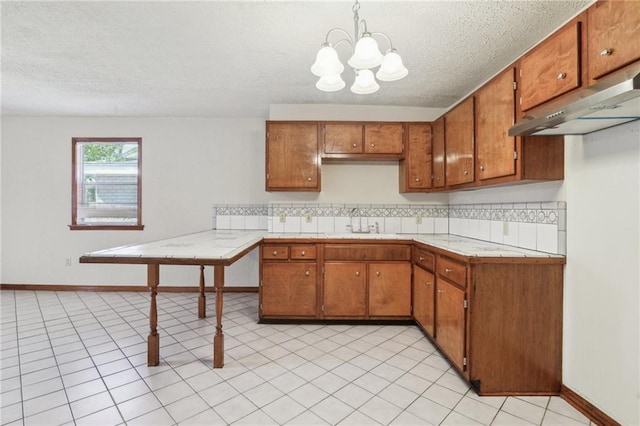 2617 Danneel St, New Orleans, LA 70113 - kitchen featuring a sink, light countertops, a chandelier, a textured ceiling, and brown cabinetry