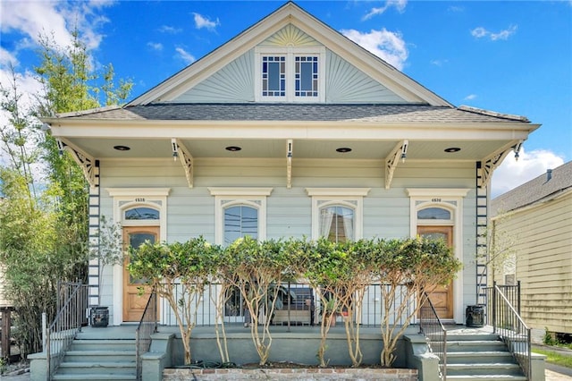 view of front of home with central AC, a shingled roof, and covered porch
