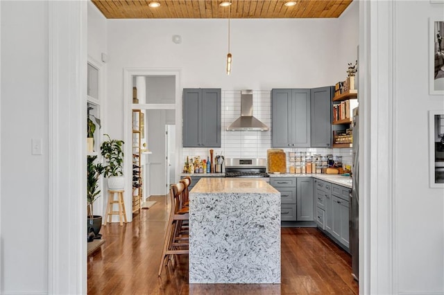 kitchen with wood ceiling, wall chimney exhaust hood, gas stove, and gray cabinets