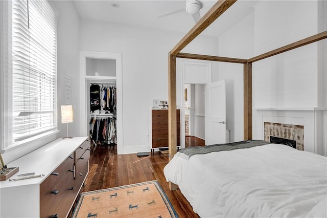 bedroom featuring a closet, ceiling fan, a fireplace, and dark wood-style floors