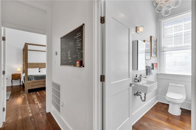 bathroom with toilet, ensuite bathroom, a wealth of natural light, and hardwood / wood-style flooring
