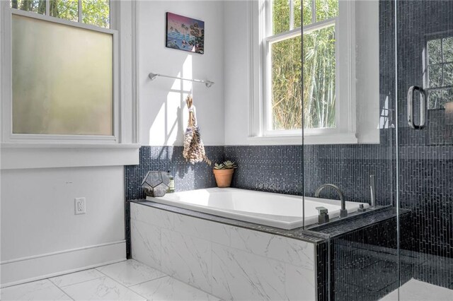 full bathroom featuring marble finish floor, a garden tub, and a stall shower