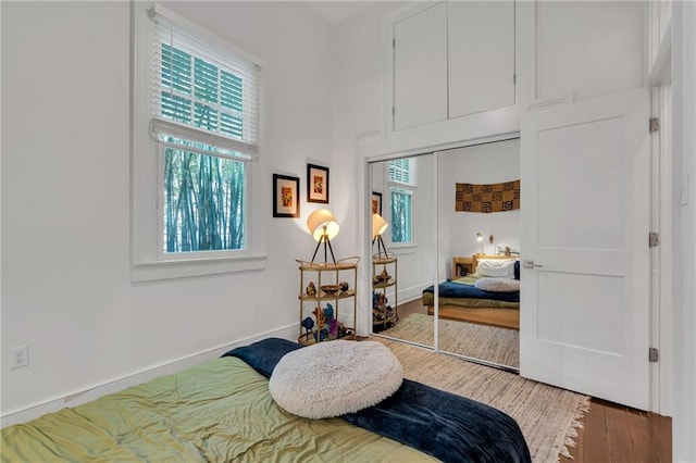 bedroom featuring a closet, baseboards, multiple windows, and wood finished floors