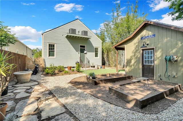 back of property with a garden, entry steps, and fence