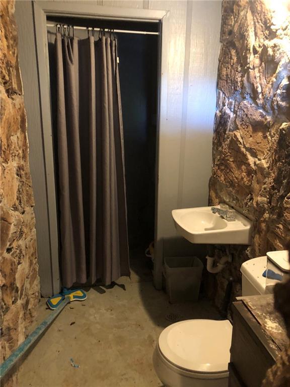 bathroom featuring unfinished concrete floors, toilet, and a sink