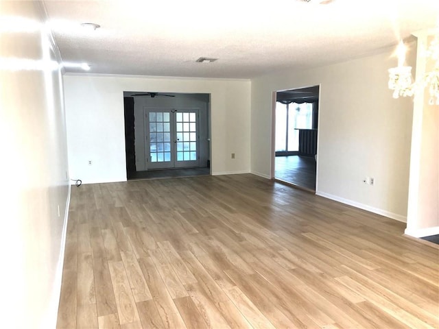 empty room featuring plenty of natural light, baseboards, a notable chandelier, and light wood-style flooring