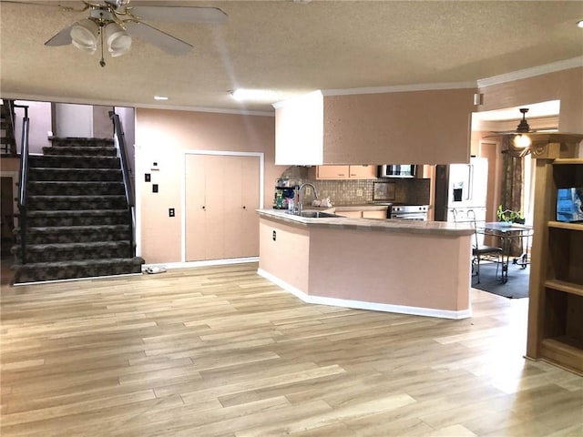 kitchen featuring a ceiling fan, a sink, decorative backsplash, appliances with stainless steel finishes, and ornamental molding