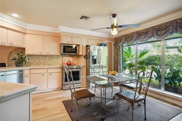 kitchen featuring light wood-style floors, crown molding, ceiling fan, visible vents, and appliances with stainless steel finishes