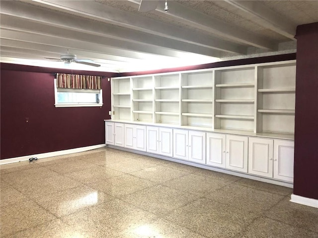 empty room featuring beam ceiling, baseboards, ceiling fan, and granite finish floor