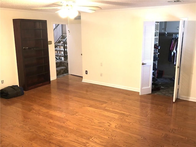 unfurnished bedroom with visible vents, wood-type flooring, a walk in closet, a closet, and baseboards