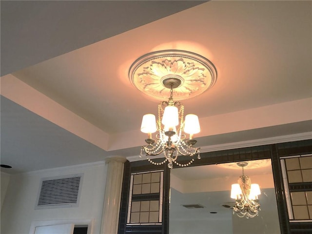 room details with ornamental molding, visible vents, a chandelier, and a raised ceiling