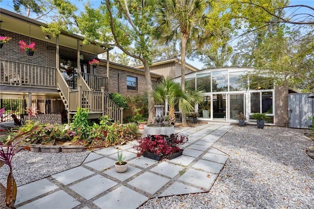 back of property with a sunroom and stairway
