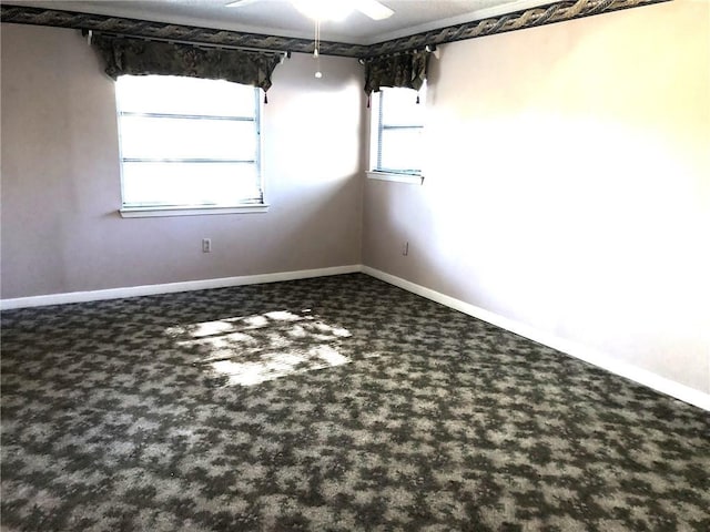empty room with carpet flooring, a ceiling fan, and baseboards