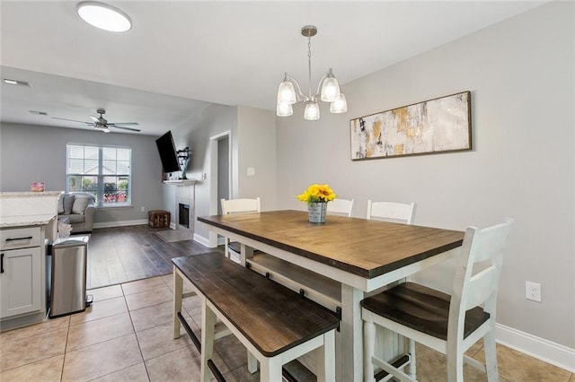 309 Allie Ln, Luling, LA 70070 - dining space featuring visible vents, light tile patterned floors, baseboards, a fireplace, and ceiling fan with notable chandelier