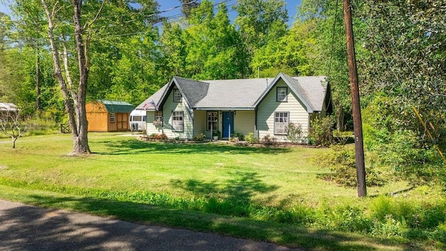 view of front of home featuring a storage unit, a front yard, and an outdoor structure