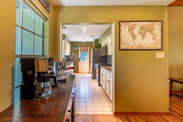 interior space with light tile patterned floors, dark countertops, white cabinets, decorative backsplash, and appliances with stainless steel finishes