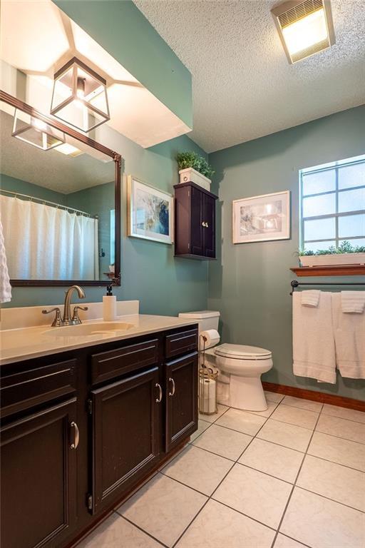 bathroom with vanity, toilet, tile patterned flooring, and a textured ceiling