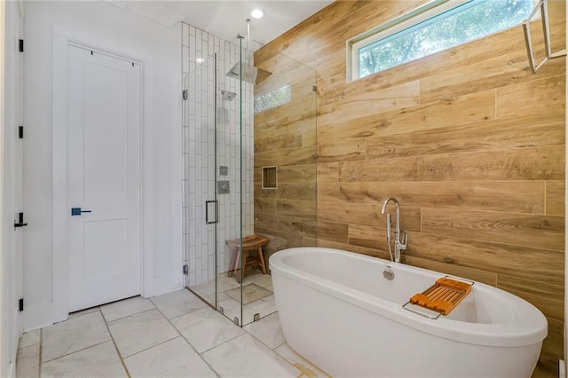 full bath featuring a shower stall, a freestanding tub, and wooden walls