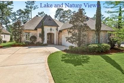french country home with a front yard, an attached garage, and driveway